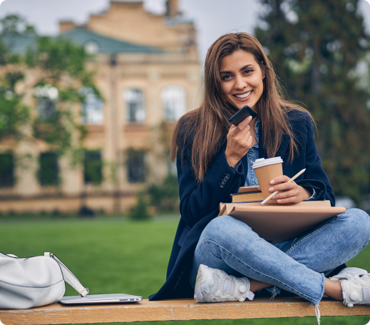 attractive-student-casual-clothes-talking-phone-while-sitting-bench-with-books-coffee 1